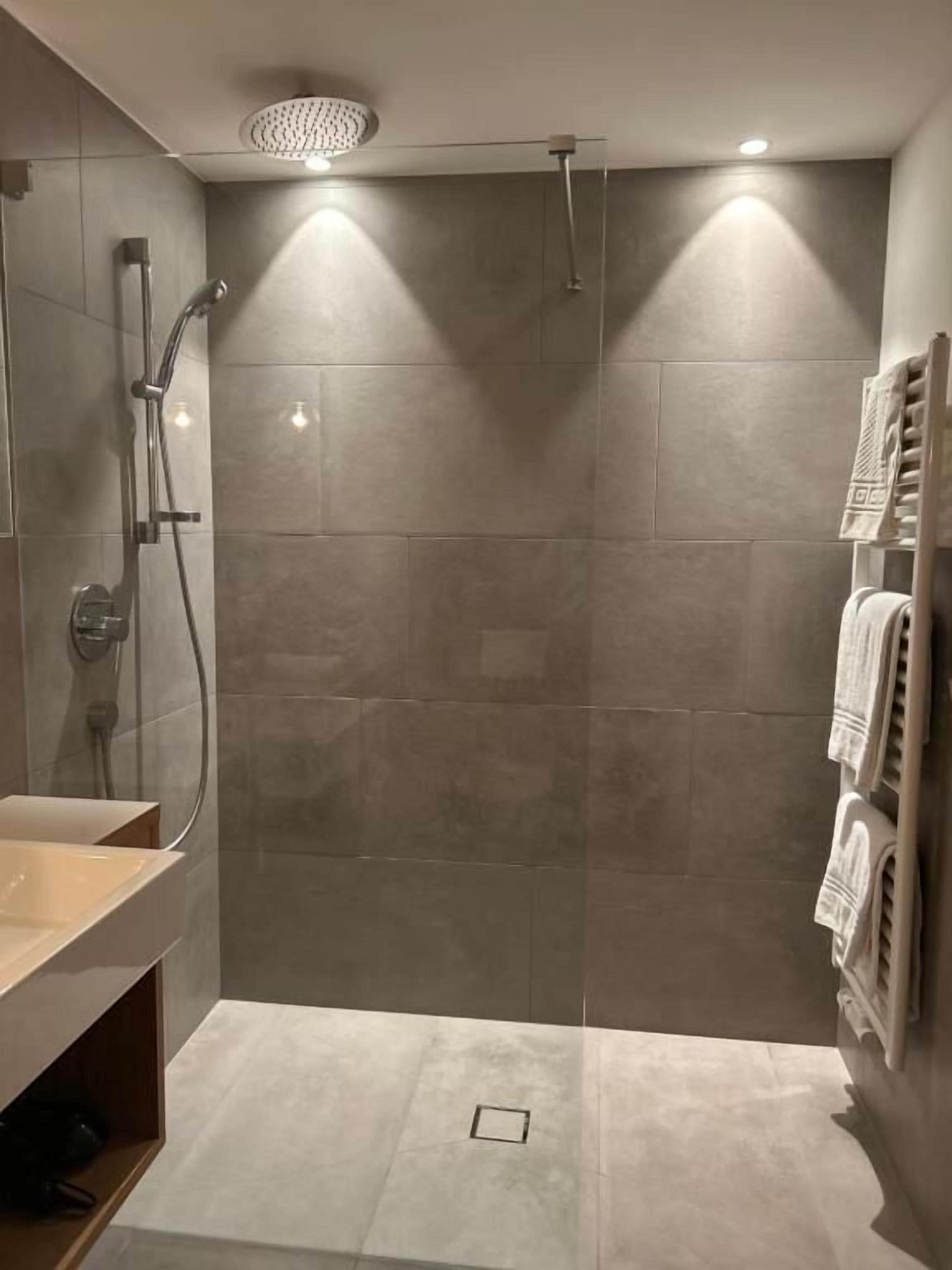 A modern bathroom with a shower, a sink, and a towel rack.