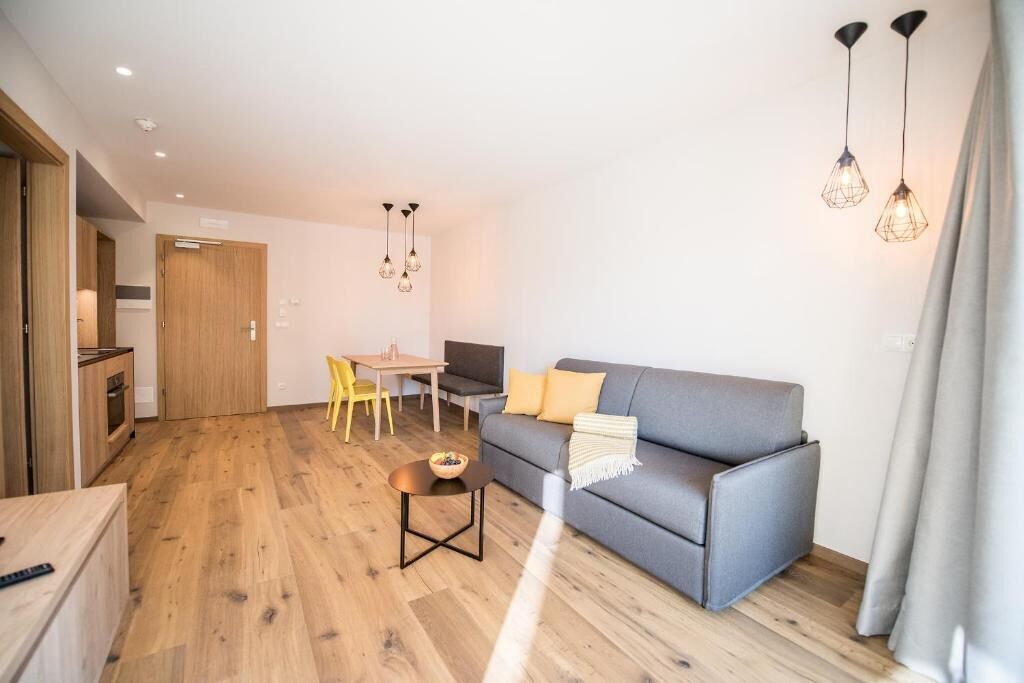 A modern living room with a sofa, a dining table, and a kitchen area.