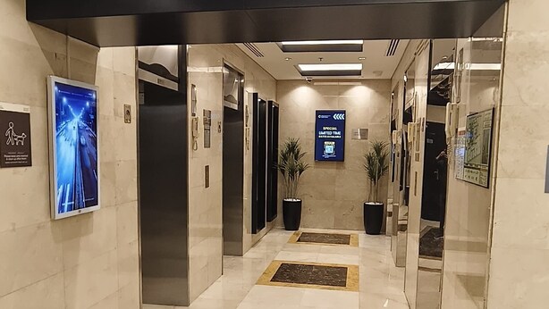 A modern hotel lobby with a marble floor, elevators, and a digital display. - Dubai gate-2 (Dubai)