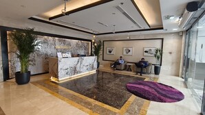 A hotel lobby with a reception desk, seating area, and large potted plants. - Dubai gate-2 (Dubai)