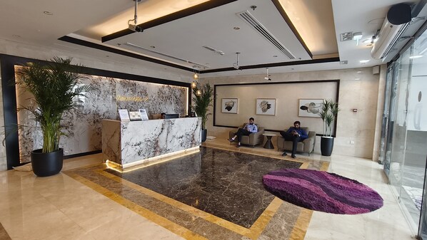 A hotel lobby with a reception desk, seating area, and large potted plants. - Dubai gate-2 (Dubai)