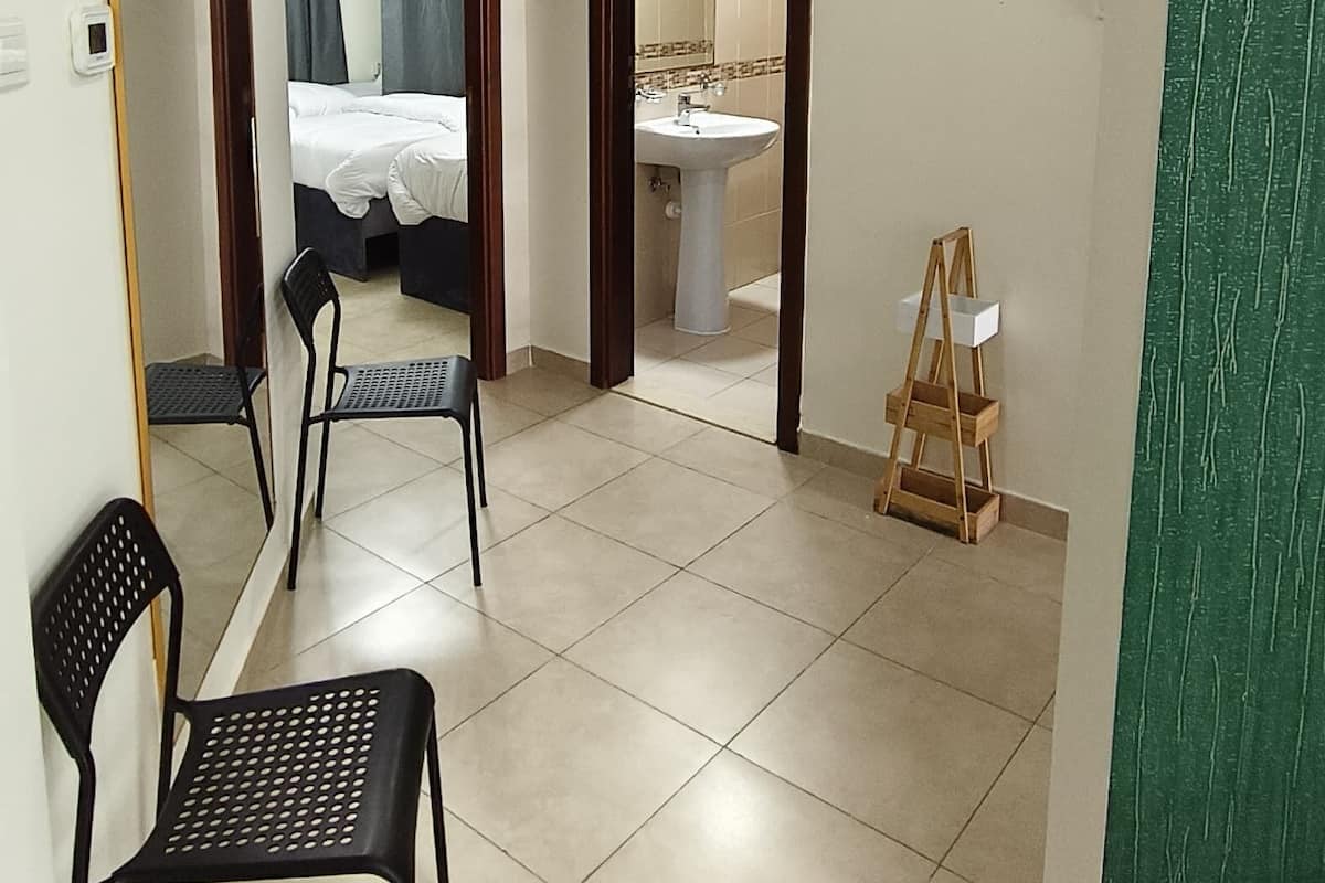 A hotel room with a bed, a bathroom, a mirror, and a chair.