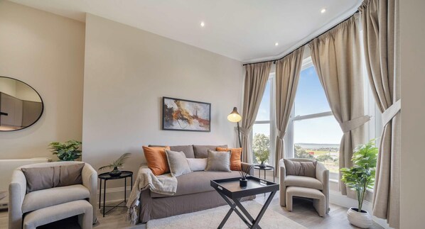 Una sala de estar moderna con un sofá, sillones, una mesa de centro y vistas al exterior.