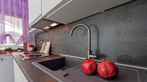 Eine moderne Küche mit Spüle aus Edelstahl, einer Granatapfel und einem roten Wasserkocher.