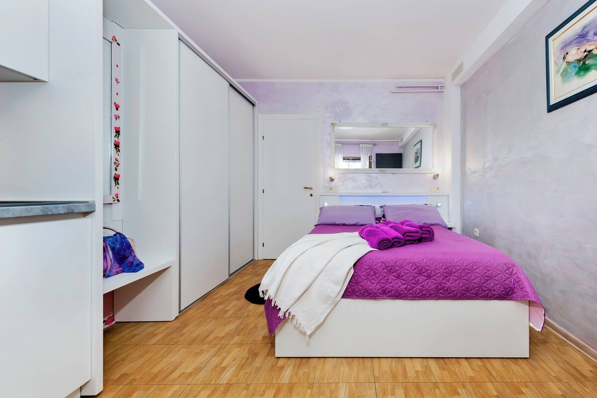 A bedroom with a bed, a wardrobe, a mirror, and a bathroom.