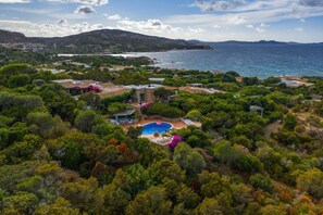 Ein Küstenanwesen mit Pool, umgeben von üppiger Vegetation und Blick auf das Meer.