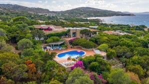 Una villa con piscina rodeada de exuberante vegetación y vista al mar.