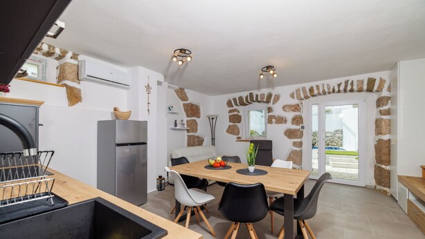 Cozinha moderna com área de refeições, detalhes em parede de pedra e vista para o exterior.