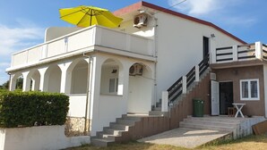 Un bâtiment à deux étages avec un escalier, un parapluie jaune et une petite table à l’extérieur.