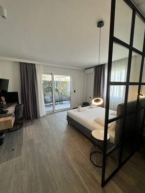 A modern hotel room with a bed, desk, and a view of the outdoors. - Casa Divinus (Athens)