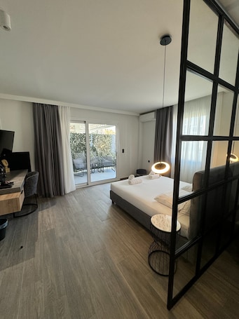 A modern hotel room with a bed, desk, and a view of the outdoors.