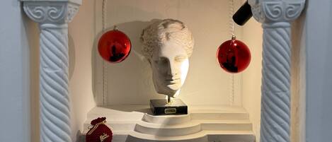 A marble bust on a pedestal, a red ornament, and a small red gift box.
