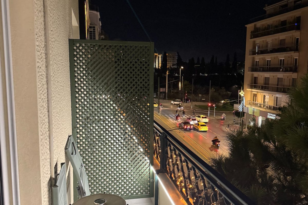 A balcony with a view of a street at night, a patterned wall, and a table with chairs.