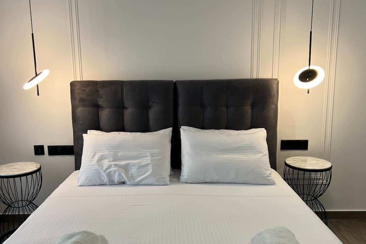 A hotel room with a large bed, two bedside tables, and two pendant lights.