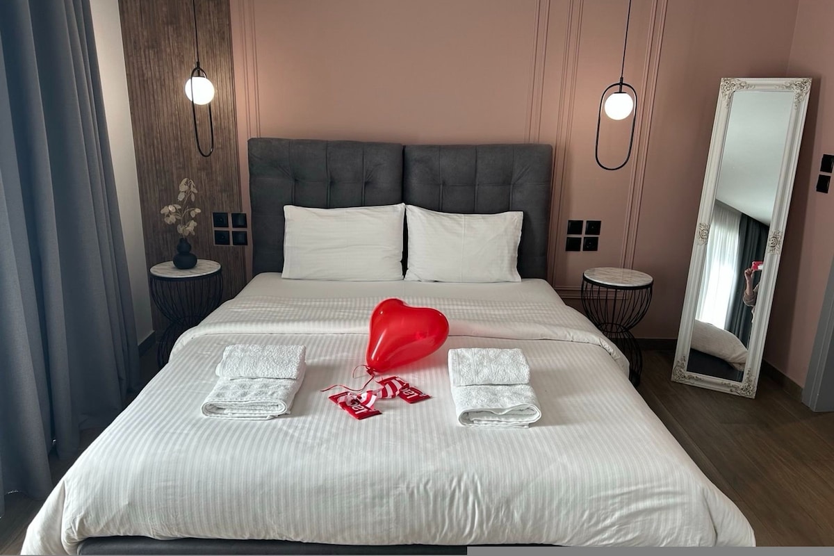 A hotel room with a large bed, two bedside tables, a mirror, and a wall-mounted light fixture.