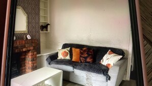 Ein Wohnzimmer mit einer Couch, einem Couchtisch, einem Kamin und einem Regal mit Dekoration.