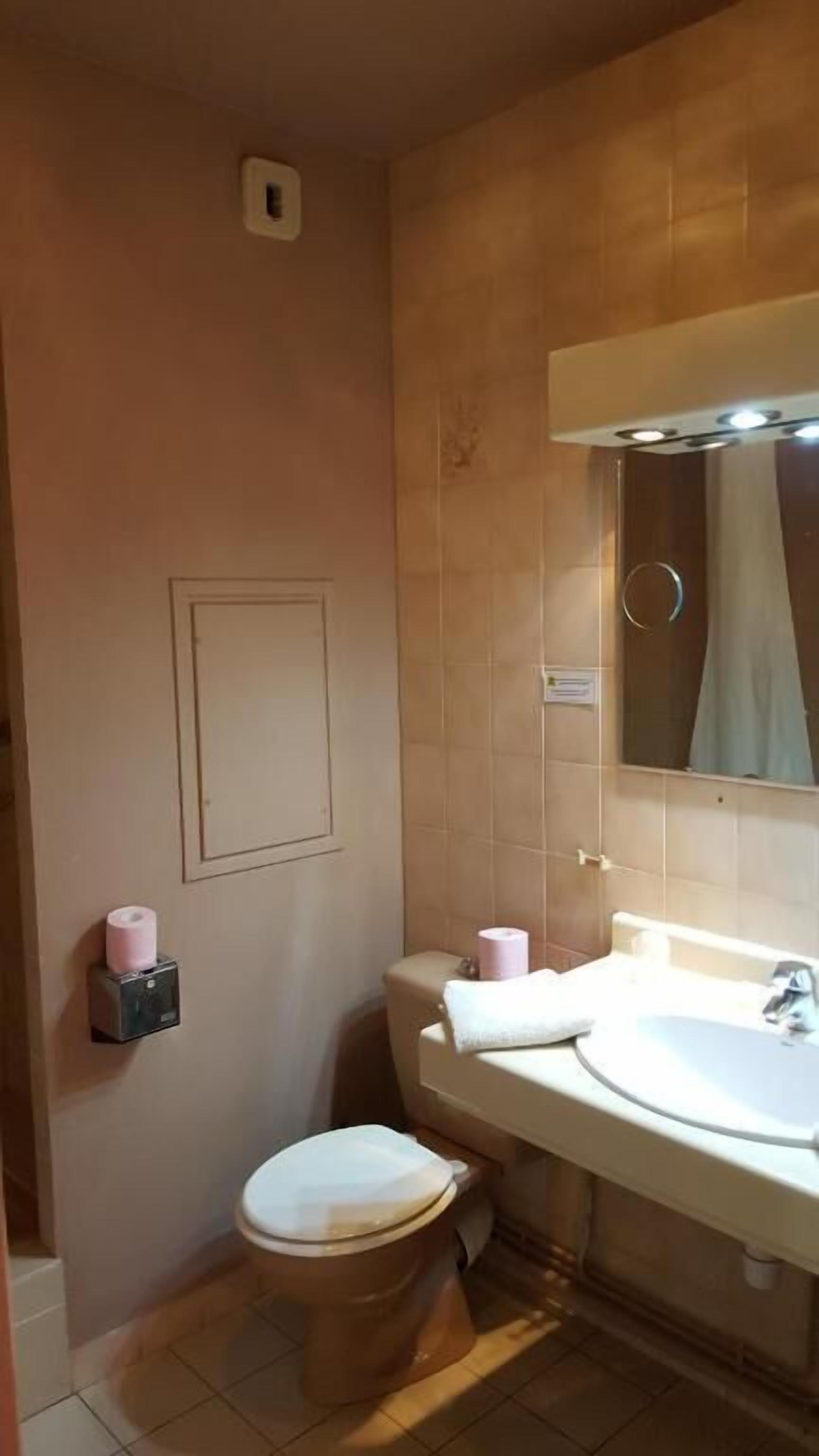 Un baño con inodoro, lavamanos y espejo.