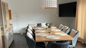 Zona pranzo moderna con tavolo in legno, sedie nere e lampada a sospensione.