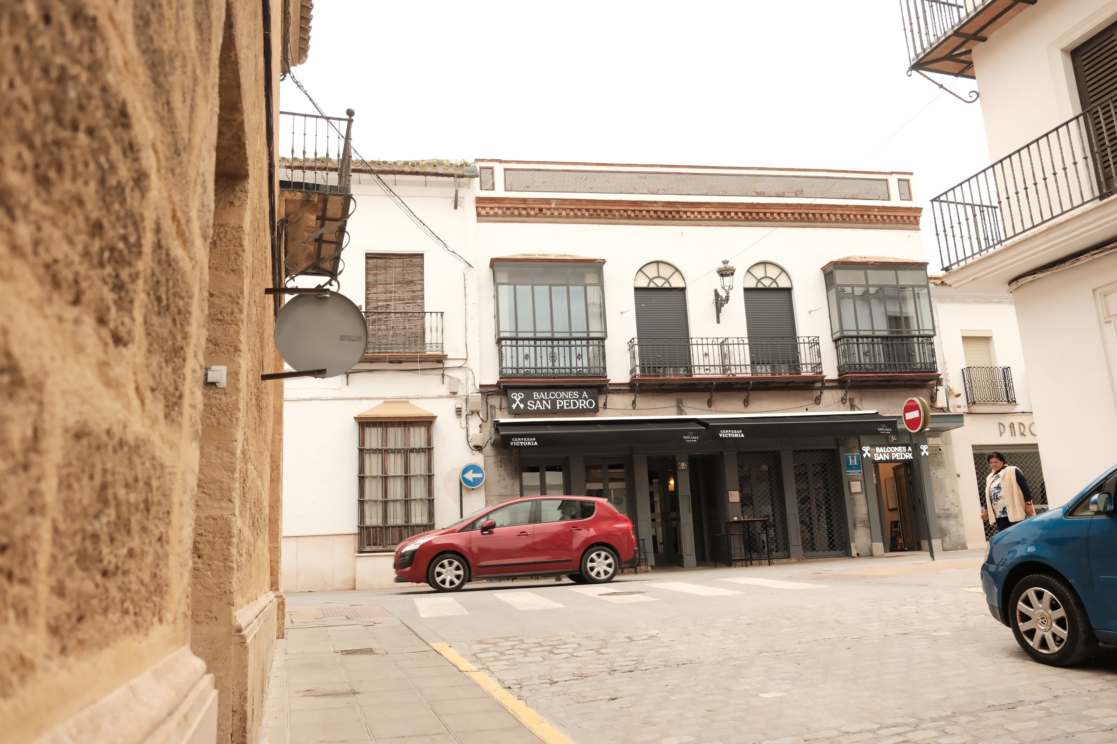 A street view with a building labeled 'BALCONES A SAN PEDRO' and a red car parked in front.