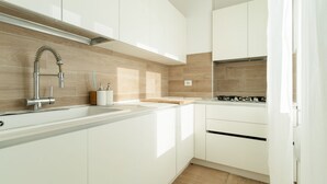 A modern kitchen with white cabinets, a stainless steel faucet, and a wooden backsplash. - GuestHost - Spacious 90m2 apartment, ideal for up to 6 people, located on the fourth floor of a building with lift.The accommodation is located in Municipality 4, within the Forlanini/Mecenate district, in the eastern area of ​​Milan, a predominantly (Milan)