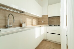 Eine moderne Küche mit weißen Schränken, einem Edelstahlarmaturen und einer Holzrückwand.