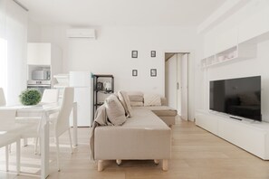 Ein modernes Wohnzimmer mit Sofa, Fernseher und Küchenbereich.