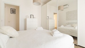 A modern hotel room with a large bed, a dresser, a mirror, and a wall-mounted air conditioning unit. - GuestHost - Spacious 90m2 apartment, ideal for up to 6 people, located on the fourth floor of a building with lift.The accommodation is located in Municipality 4, within the Forlanini/Mecenate district, in the eastern area of ​​Milan, a predominantly (Milan)