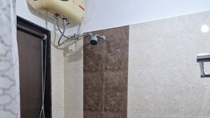Ein Badezimmer mit Dusche, Handtuchhalter, Eimer und Warmwasserbereiter.