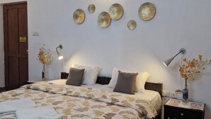Ein Schlafzimmer mit Bett, Nachttischen, Wanddekoration und einer Tür.