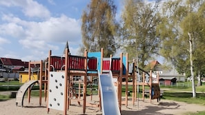 Ein Spielplatz mit Klettergerüsten, einer Rutsche und einer Schaukel.
