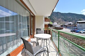 Un balcon avec une table et des chaises, donnant sur un parking, avec des bĂątiments en arriĂšre-plan.