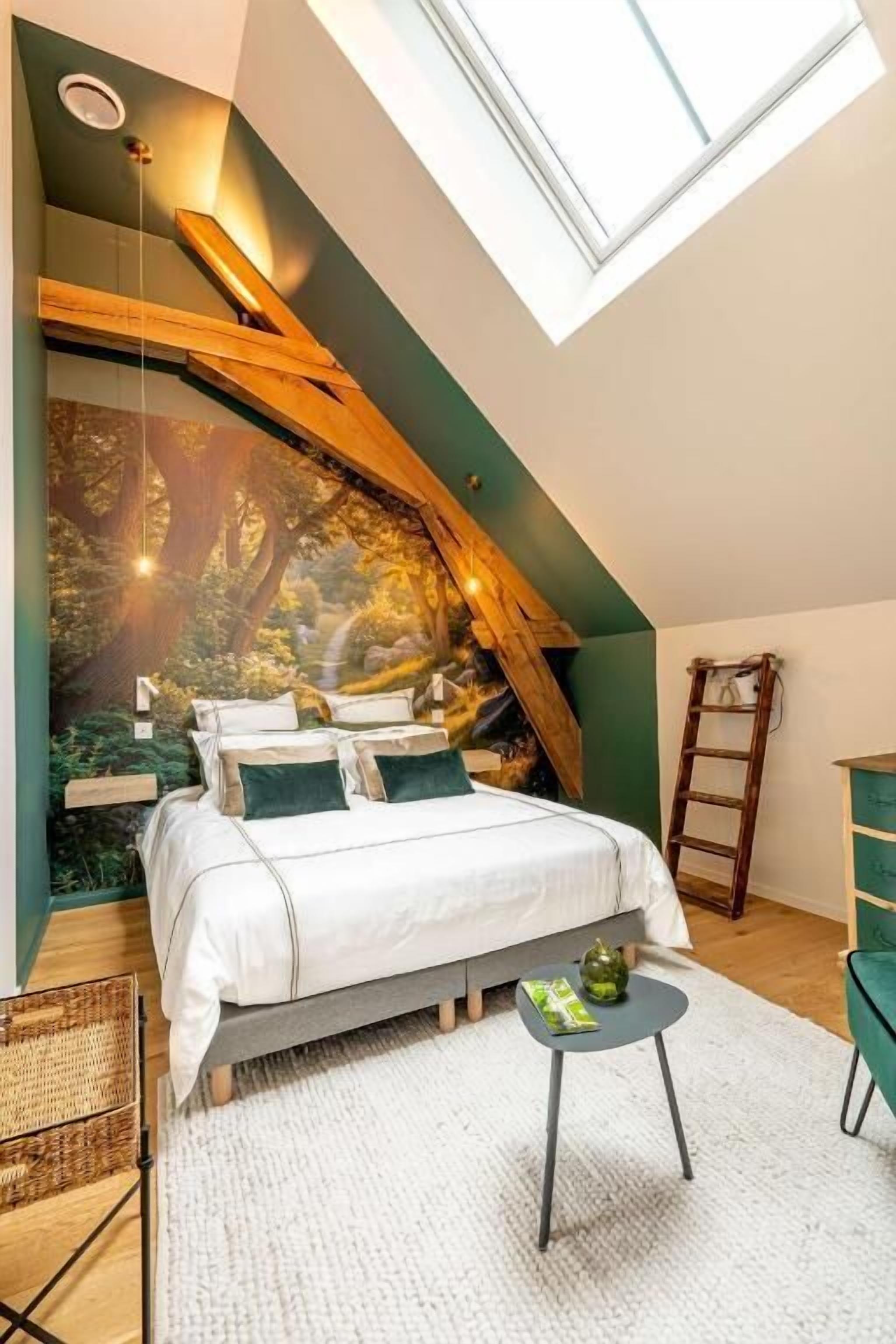 A bedroom with a sloped ceiling, a bed, a small table, and a ladder.