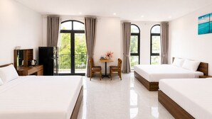 A hotel room with two beds, a desk with a chair, a small table with a vase, and large windows with curtains. - Dumi Havana Homestay Grand World Phu Quoc (Phu Quoc)
