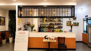 A cafe with a whiteboard menu, a counter with various items, and a seating area with a chair. - Dumi Havana Homestay Grand World Phu Quoc (Phu Quoc)