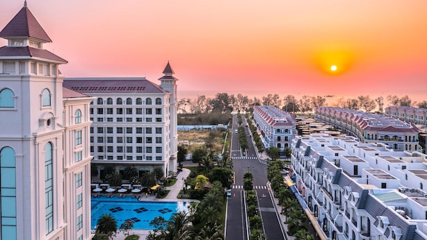 A hotel with a swimming pool, a large building with a tower, and a row of colorful buildings.
