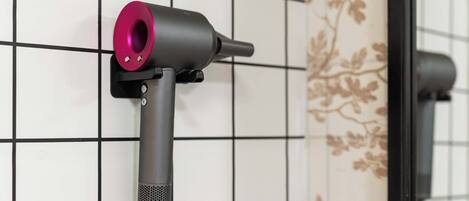 A hairdryer mounted on a tiled wall with a floral pattern.
