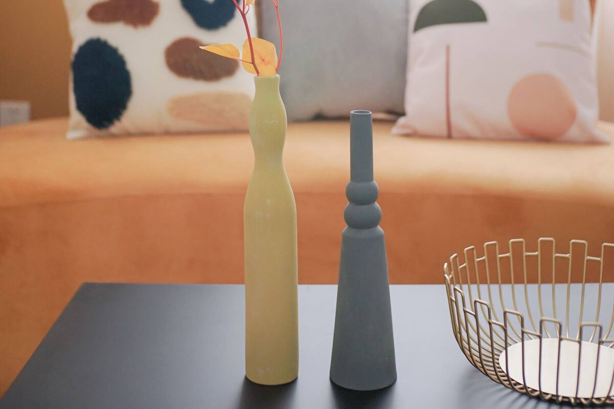 Una mesa con un florero, una vela y una cesta de alambre.