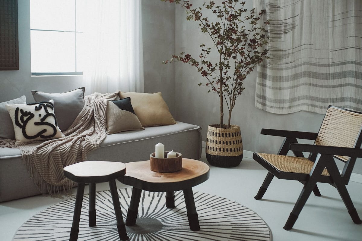 Una sala de estar moderna con un sofá, una mesa redonda de madera, una silla y una planta en maceta.