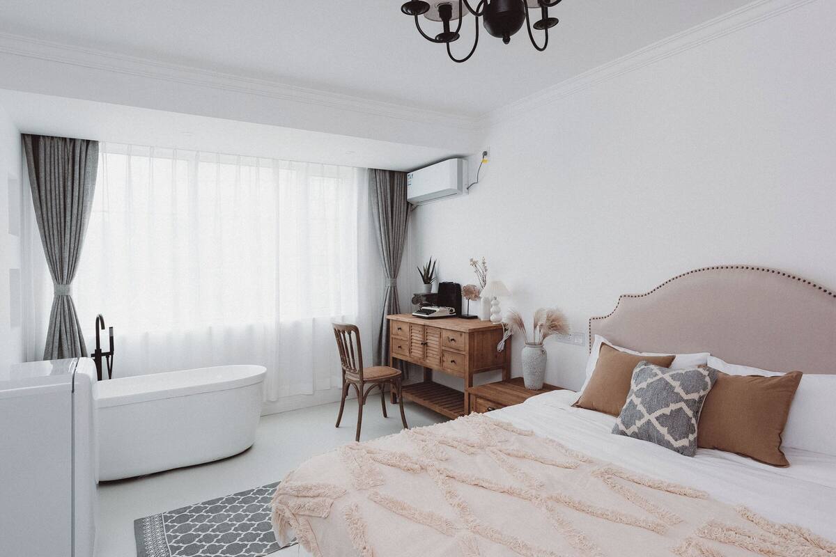 Un dormitorio con cama, cómoda, silla, tocador y bañera.