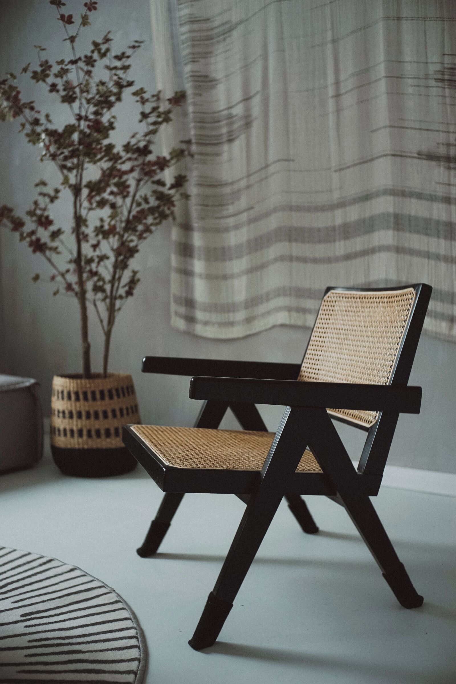 A modern chair with a woven backrest and seat, positioned on a light-colored floor.