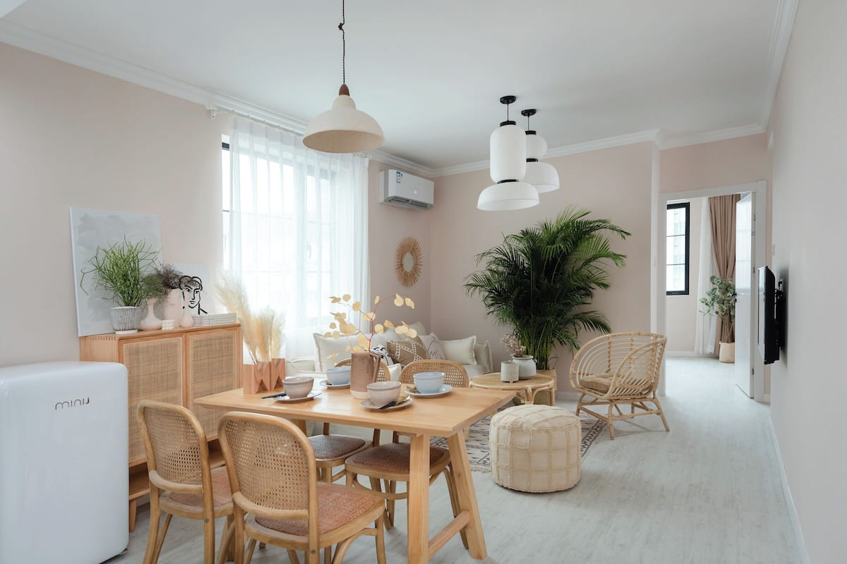 Un comedor con una mesa de madera, sillas de mimbre y un refrigerador blanco.