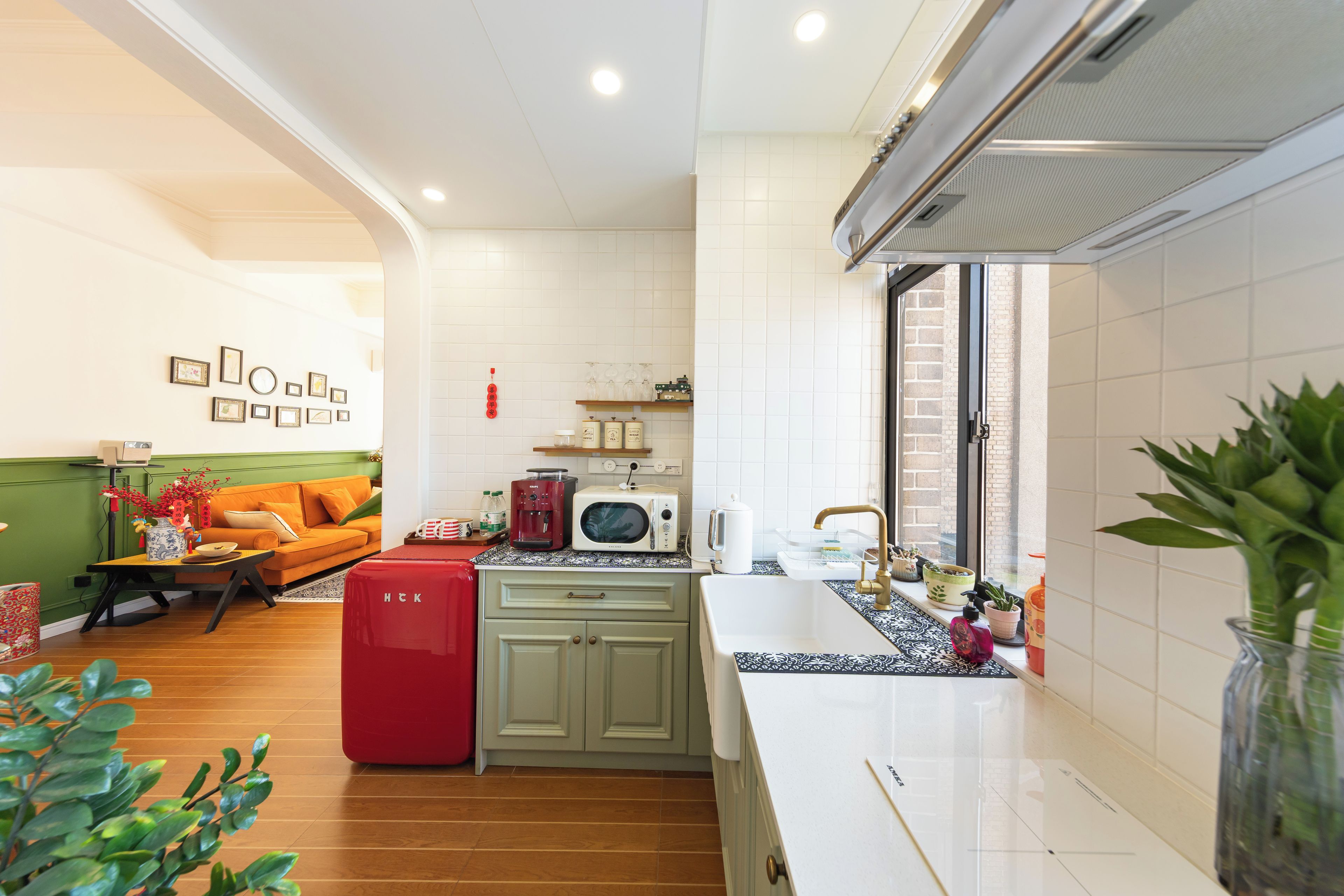 A modern kitchen with a microwave, coffee maker, and a red refrigerator.