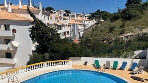 A swimming pool with a yellow and white poolside, surrounded by lounge chairs and a flower arrangement. - Apartment 'Madalena' with Private Pool, Wi-Fi and Air Conditioning (Carvoeiro)