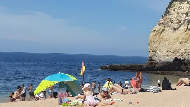 A beach with people sunbathing, a large rock formation, and a clear blue sky. - Apartment 'Madalena' with Private Pool, Wi-Fi and Air Conditioning (Carvoeiro)