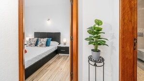 A bedroom with a bed, bedside table, and a potted plant. - Apartment 'Madalena' with Private Pool, Wi-Fi and Air Conditioning (Carvoeiro)