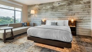 Une chambre d’hôtel avec un lit, un canapé, une petite table et une grande fenêtre.