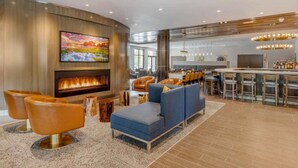 Un salon moderne doté d’une cheminée, de sièges confortables, d’un coin bar et d’un grand téléviseur.