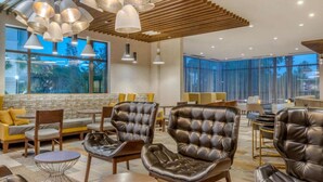 Un espacio lounge moderno con sillones de cuero, mesas redondas e iluminación colgante.