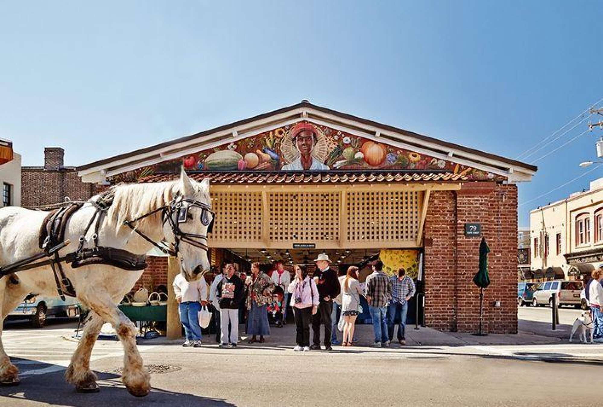 Een gebouw met een opvallende muurschildering, een paard en een menigte mensen.