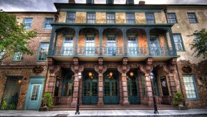 Un edificio histórico con detalles arquitectónicos ornamentales, que incluye una entrada destacada con columnas y un balcón.